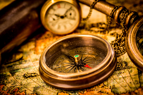 Vintage compass lies on an ancient world map.