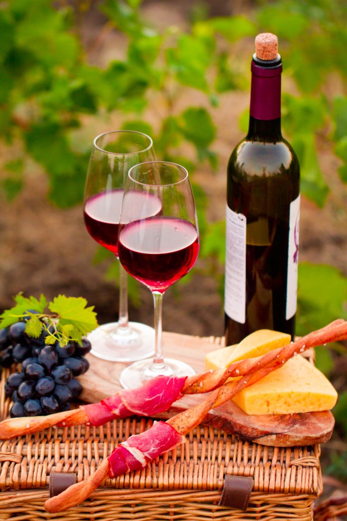 Two glasses of red wine with bottle,  bread, meat, grape and che